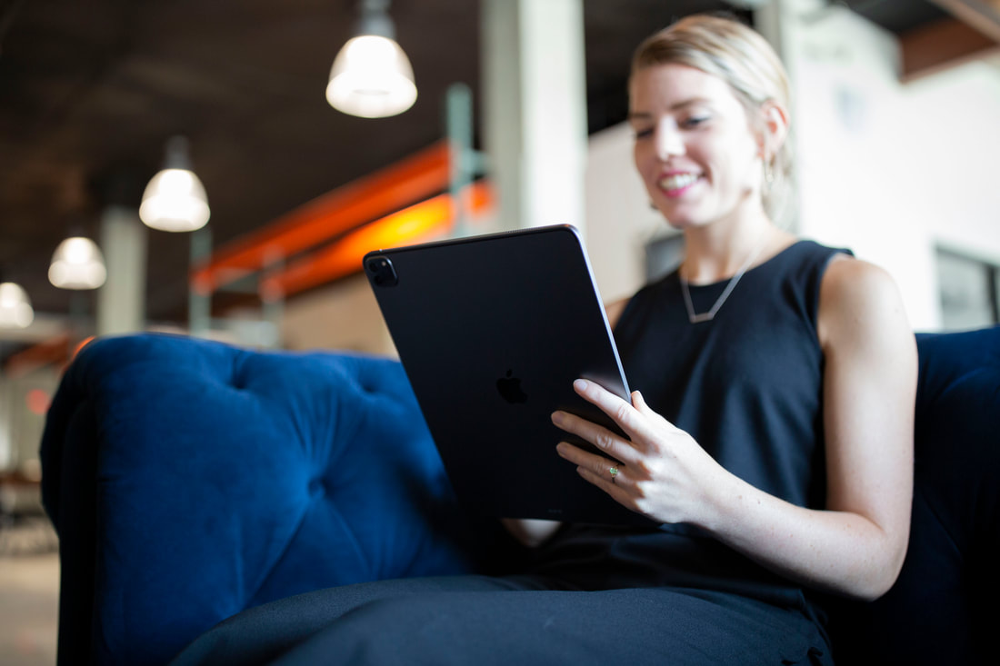 Young woman holding iPad while sitting on a couch