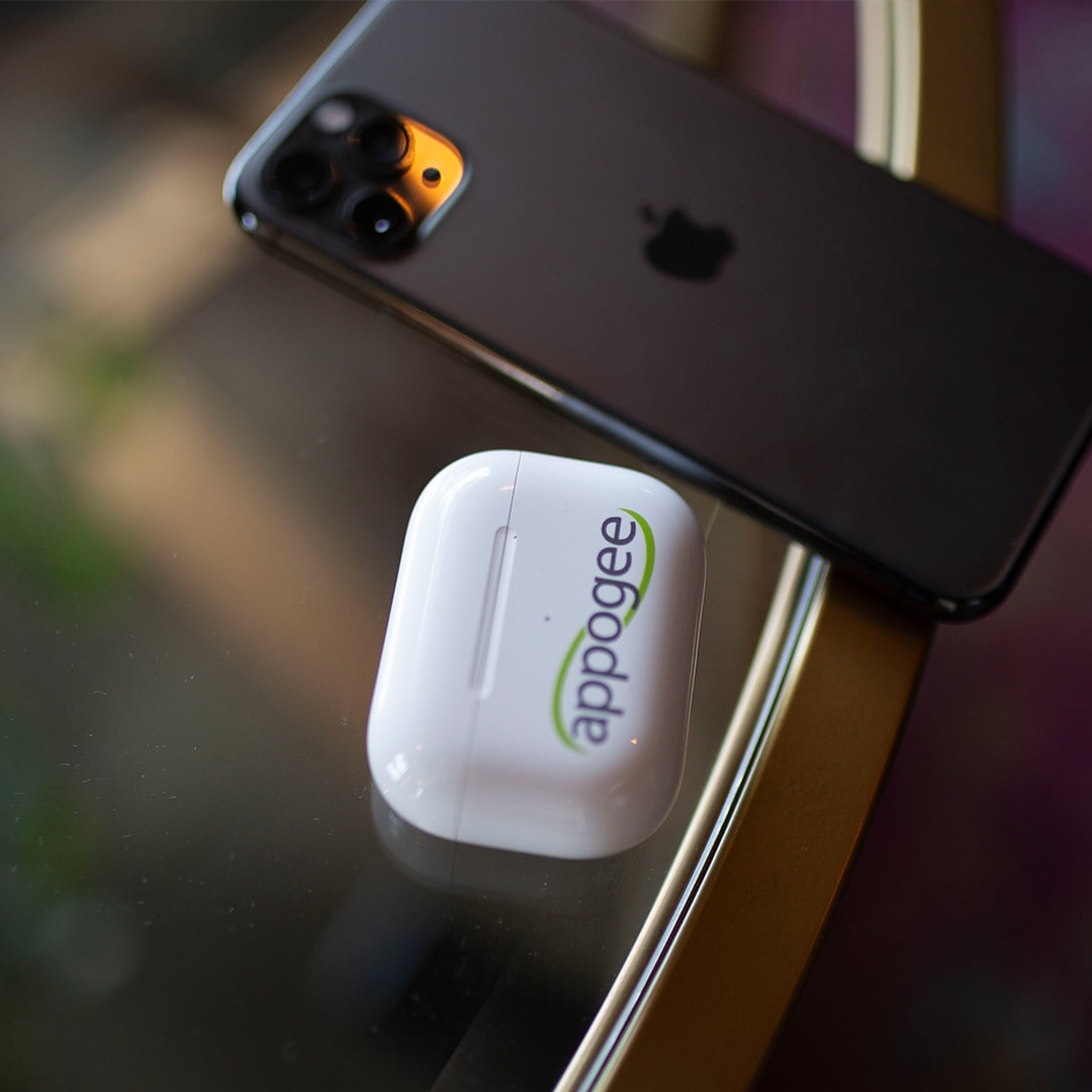 Appogee AirPods and iPhone sitting on a glass table