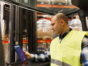 Man holding out iPad with TRUCE softward on screen while working in a factory